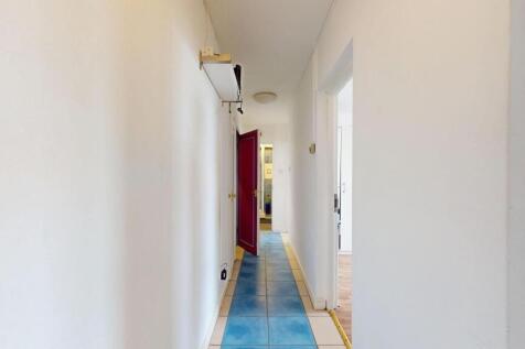 Bright, clean hallway with white walls, tiled f...