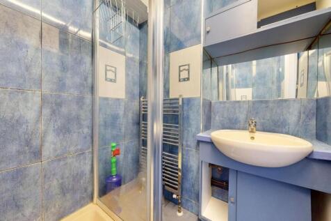 Compact blue-tiled bathroom featuring a corner ...