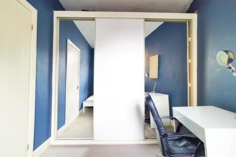 A tidy bedroom with deep blue walls, featuring ...