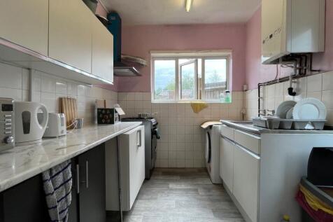 Bright galley kitchen with white cabinetry, lam...
