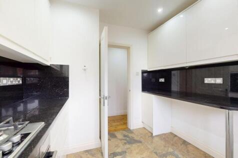 Sleek galley-style kitchen with glossy black wo...