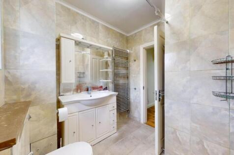 Bright, tiled bathroom with a fitted vanity uni...