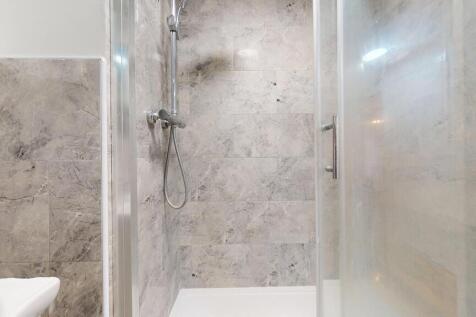 Modern tiled bathroom with a glass-enclosed wal...