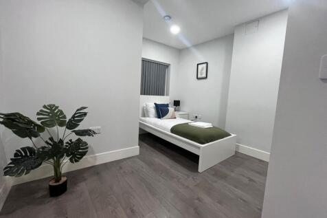 Bright, modern single bedroom with clean white ...