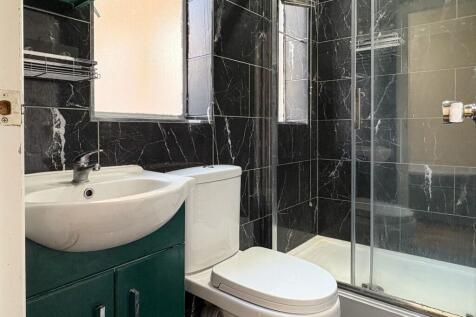 Modern bathroom with black marble-effect tiled ...