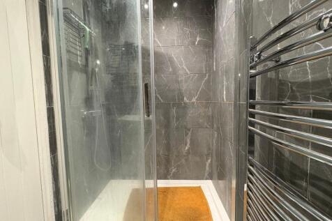 Modern shower enclosure with dark marble-effect...
