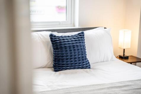 A cozy double bedroom featuring a plush white b...