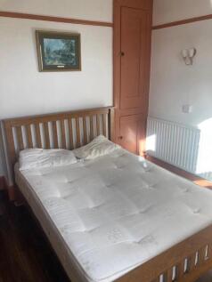 A bright double bedroom featuring a wooden bed ...