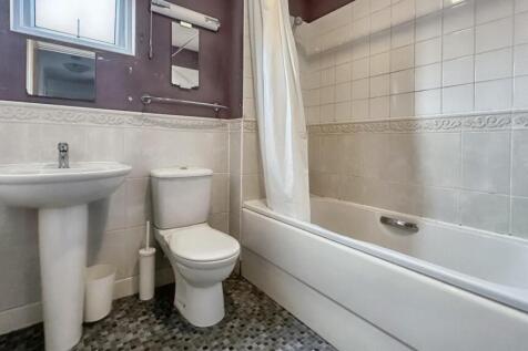 A clean bathroom featuring a bath, sink, and to...