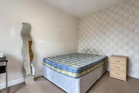 A simple double bedroom featuring a bed and a m...