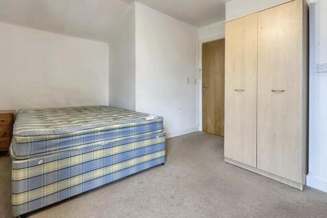 A simple double bedroom with a bed and fitted w...