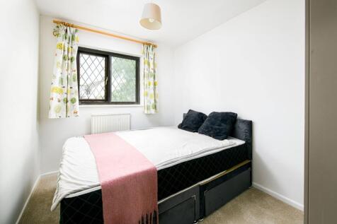 A tidy and well-lit double bedroom with a bed a...