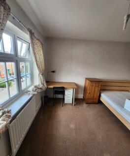 A cozy single bedroom featuring a large window ...