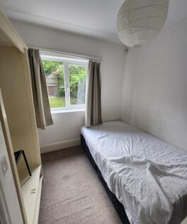 A cozy single bedroom featuring a comfortable b...