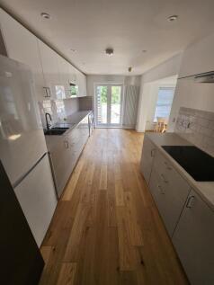 Modern and sleek kitchen featuring white cabine...