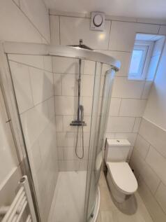 A modern bathroom featuring a curved glass show...