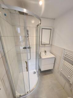 Modern bathroom featuring a curved glass shower...