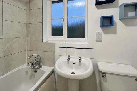 A bright and tidy bathroom featuring a bath and...