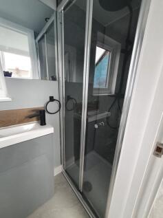 Modern bathroom featuring a sleek glass shower,...