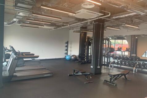 A spacious and well-lit gym equipped with moder...