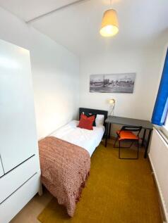 A bright and tidy single bedroom with a cozy at...