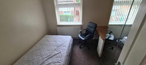 A cozy double bedroom featuring a desk and chai...