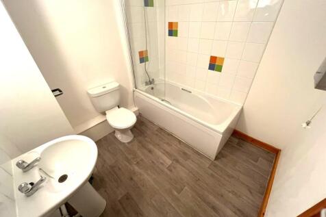 A bright and tidy bathroom featuring a bath and...