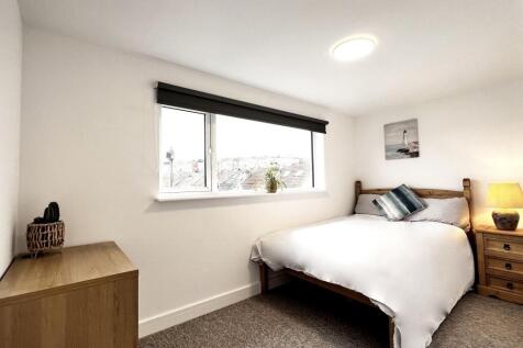 A bright double bedroom featuring a comfortable...