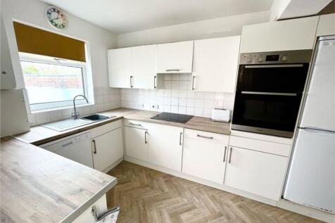 A bright and modern kitchen featuring ample sto...