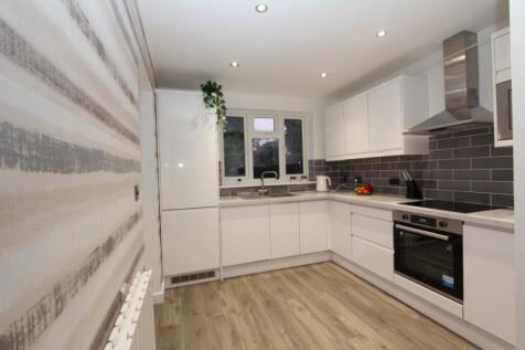 Modern kitchen featuring sleek white cabinetry,...