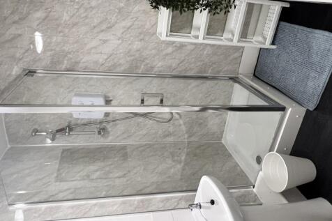 A modern bathroom featuring a spacious shower a...
