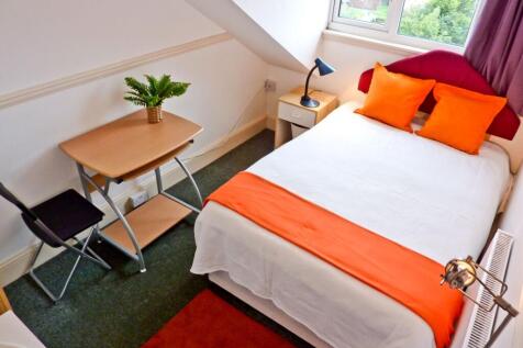 A cozy double bedroom featuring vibrant orange ...