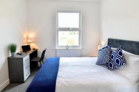 This spacious double bedroom features a comfort...