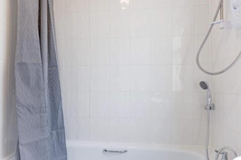 A bright and clean bathroom featuring a bathtub...