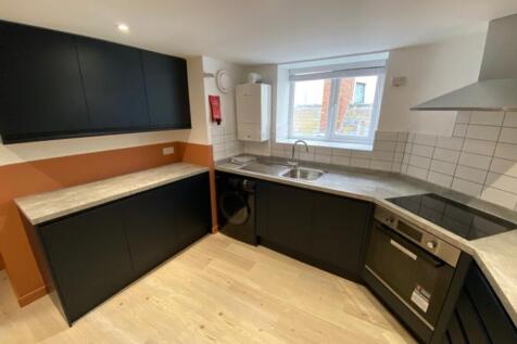 Modern kitchen featuring sleek black cabinetry,...