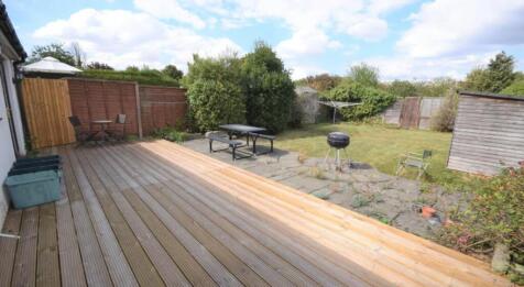 A spacious garden featuring a wooden deck, perf...