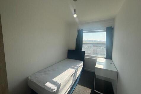 A well-lit single bedroom featuring a comfortab...