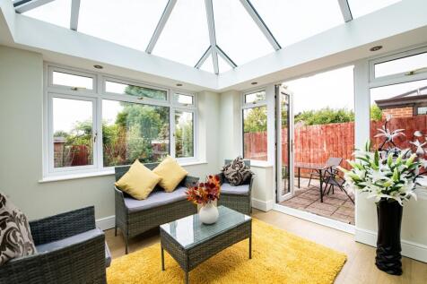 Bright and inviting garden room featuring large...