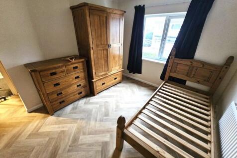 This inviting double bedroom features warm wood...
