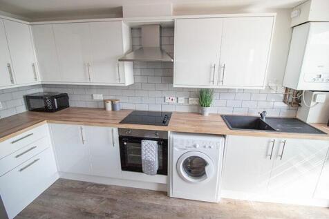 This modern kitchen features sleek white cabine...