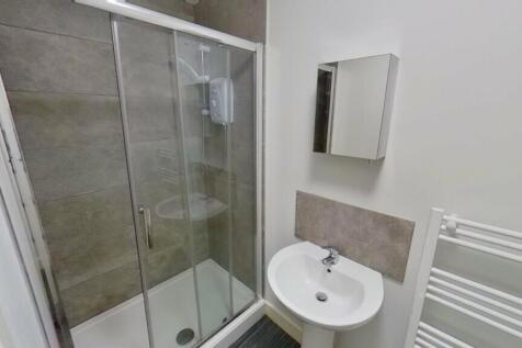 A modern bathroom featuring a sleek glass showe...