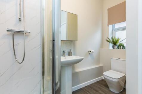 A spacious and modern bathroom featuring a slee...