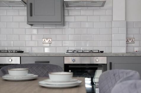 This modern kitchen features sleek gray cabinet...