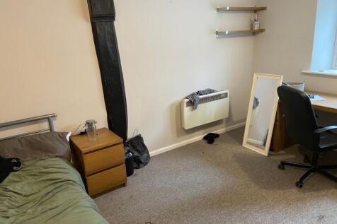 Cozy single bedroom featuring a study desk with...