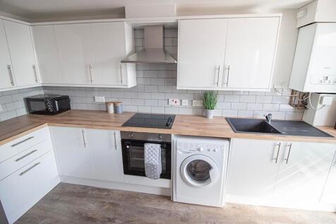 This modern kitchen features sleek white cabine...
