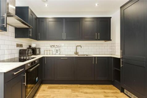 Modern kitchen featuring sleek dark cabinetry a...