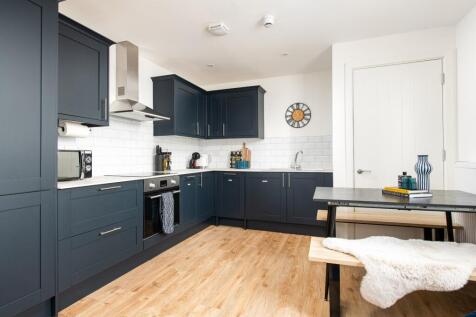This modern kitchen features sleek dark cabinet...