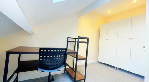 A cozy double bedroom featuring a workspace wit...