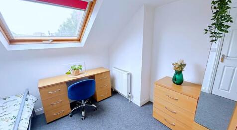 This cozy double bedroom features ample natural...