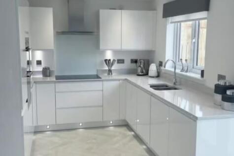 This modern kitchen features sleek white cabine...